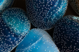 Steinluftblasen / An einigen Lapislazuli im Wasserglas haben sich Luftblasen gebildet.