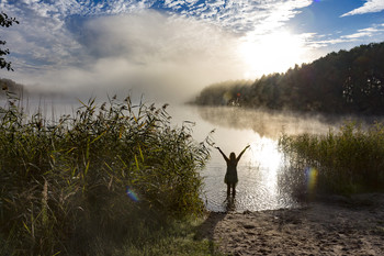 Ein Morgen am See / Eine Frau genießt den Morgen am See vor der aufgehenden Sonne im Morgennebel