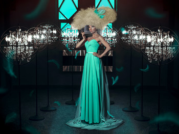 Emancipation / Woman in a teal dress wearing a bird cage through huge blond hair among several lights