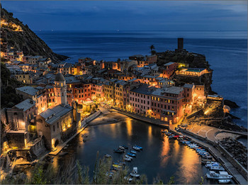 Vernazza at night / Vernazza is one of the 5 centuries-old villages of the Cinque Terre on the rugged Ligurian coast of north-western Italy. The small marina of the village is surrounded by colorful houses. The church of Santa Margherita di Antiochia has a bell tower with dome. The medieval Doria rock castle with a cylindrical tower once served as a defense; directly below lies the bastion Belforte.